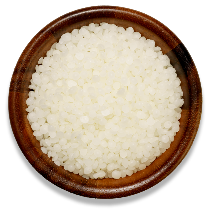 White beeswax in a brown wooden bowl on a transparent surface 